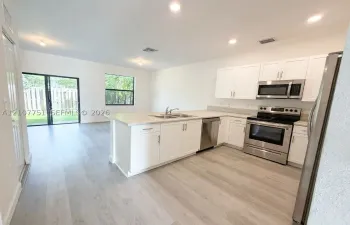Kitchen featuring white cabinetry, light-toned countertops, stainless steel appliances, recessed lighting, and wood-finish flooring