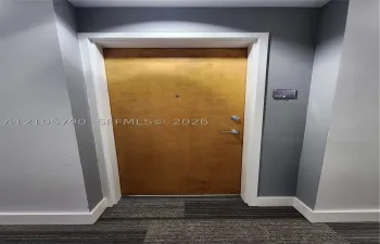 Solid-core wood-finish door with brushed metallic hardware, integrated security peephole, and white architectural casing