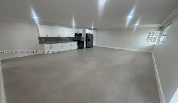 Open-concept space featuring large-format tile flooring, white shaker-style cabinetry, stone-surface countertops, recessed lighting, and a glass block window