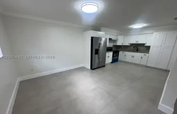 Kitchen featuring white shaker-style cabinetry, stainless steel side-by-side refrigerator, stone-composite countertops, matte black gooseneck faucet, and large-format tile flooring