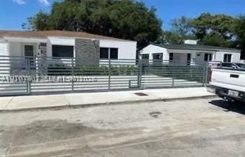 Exterior facade featuring smooth stucco finish, stone veneer accents, and metal horizontal slat fencing
