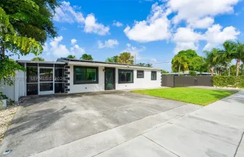 Single-story residence featuring a smooth stucco exterior with decorative corner detailing, a screened-in porch, a concrete driveway, and a fenced-in grass lawn