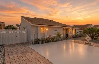 Single-story residence featuring a shed roofline, stucco exterior, paved driveway, and gated side access