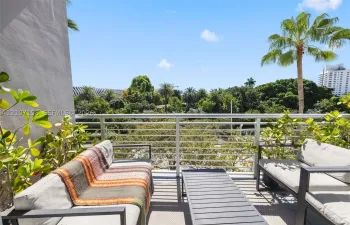 Private balcony featuring horizontal metal railing and mature tropical greenery