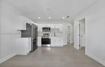 Kitchen featuring white shaker-style cabinetry, stainless steel appliances, neutral tile flooring, recessed lighting, and solid-surface countertops