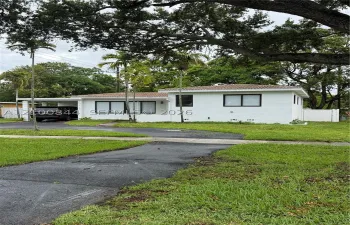 Single-story exterior featuring white masonry walls, a tile roof, an attached carport, and window frames with black trim