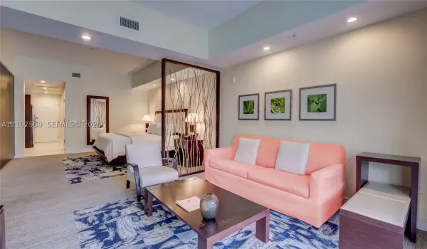 Open-concept studio space featuring recessed lighting, neutral wall paint, and a decorative wood-element room divider