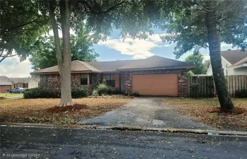 Single-story residence featuring a brick exterior, attached two-car garage, and mature landscaping