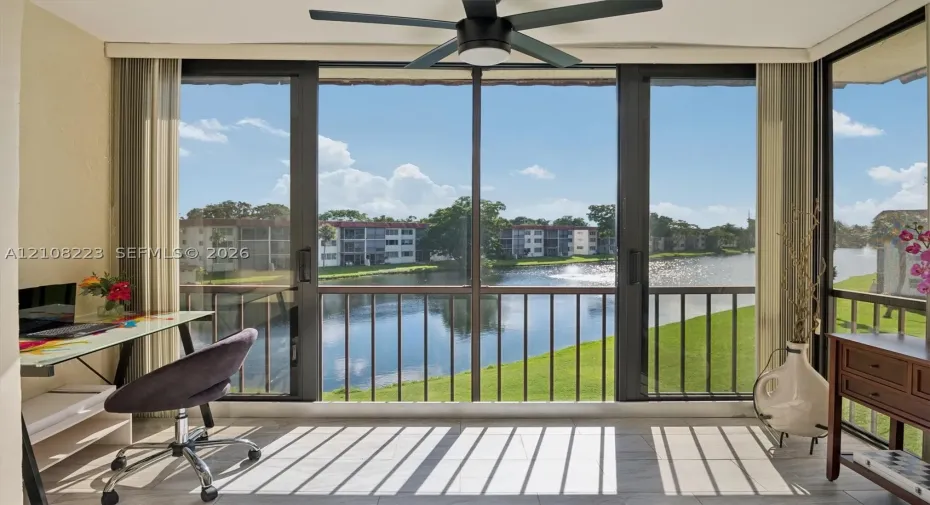 Enclosed sunroom featuring floor-to-ceiling windows, sliding glass doors, tile flooring, and a ceiling fan