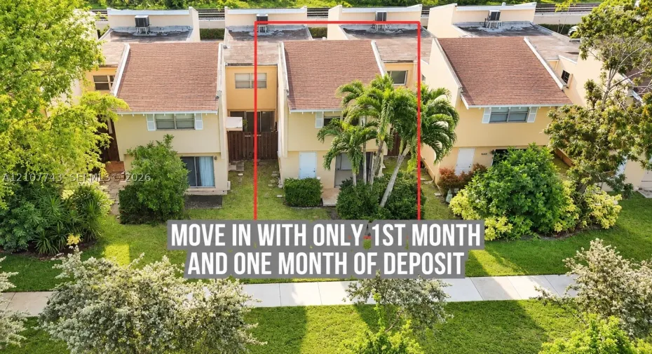 Two-story townhome exterior featuring a pitched roof, neutral stucco siding, sliding glass doors, and mature palm tree landscaping