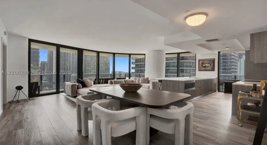 Open-concept living space featuring floor-to-ceiling windows, wood-finish flooring, a kitchen island with stone countertops, and recessed lighting