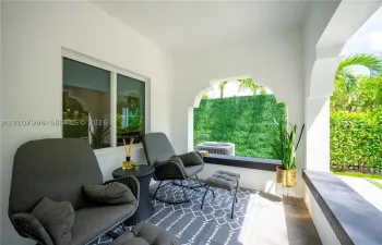 Covered porch featuring arched openings, tile flooring, and integrated concrete ledge seating