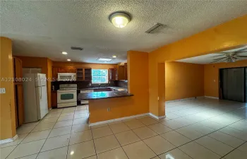 Kitchen featuring wood cabinetry, solid-surface countertops, tile flooring, and integrated white appliances