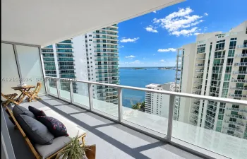 Private balcony featuring a glass-panel railing, concrete flooring, and water scenery