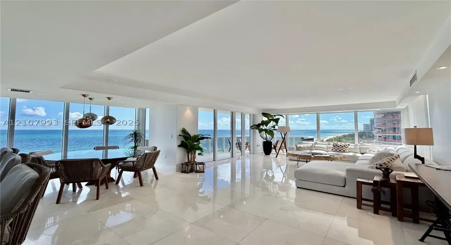 Open-concept interior featuring large-format stone flooring, floor-to-ceiling glass walls, recessed lighting, and modern pendant fixtures