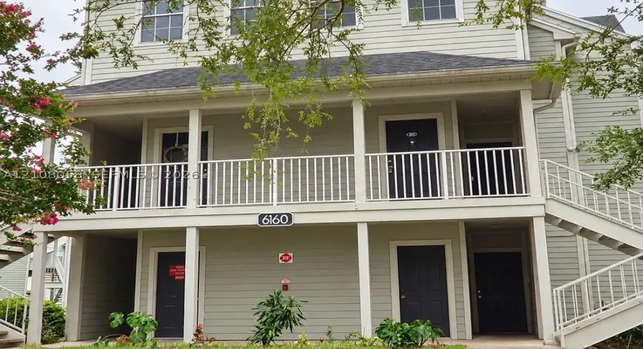 Multi-level exterior featuring light green horizontal siding, white balustrade railings, shingled roofing, and exterior metal staircases