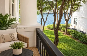 Covered patio featuring a structural column, dark-finish metal railing, manicured lawn, and water side-frontage