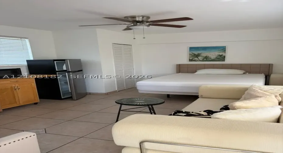 Room featuring ceramic tile flooring, built-in wooden cabinetry, louvered closet doors, and a ceiling fan