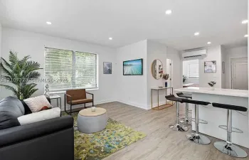 Open-concept living room with modern kitchen and wood-look flooring.