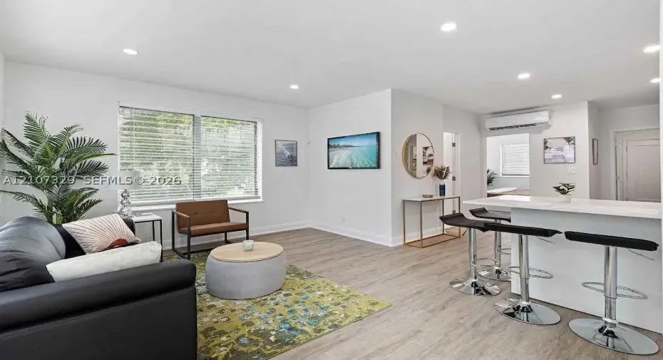 Open-concept living room with modern kitchen and wood-look flooring.