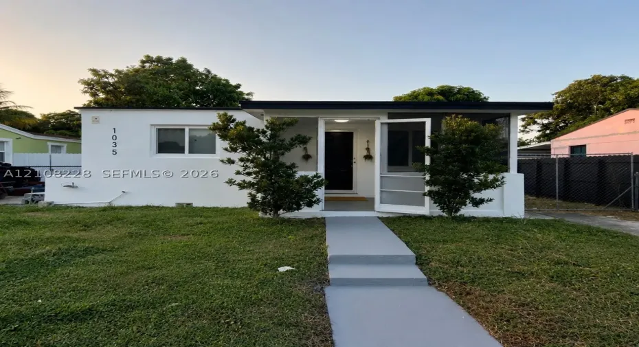 Stucco exterior with a flat roofline, covered front entryway, screen door, and paved pedestrian walkway