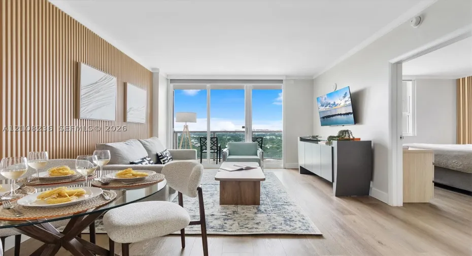 Living space featuring floor-to-ceiling glass sliding doors, wood-finish flooring, and a vertical wood-slat accent wall