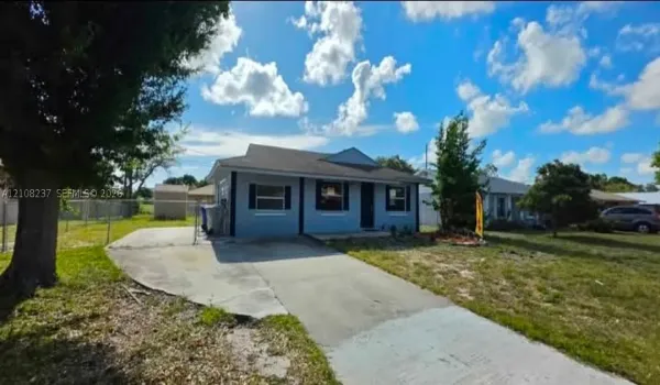 Single-story residence with a concrete driveway, multi-pane windows, decorative shutters, and an attached storage structure