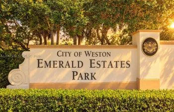 Stucco monument sign featuring raised lettering, integrated decorative medallion, and professional landscaping