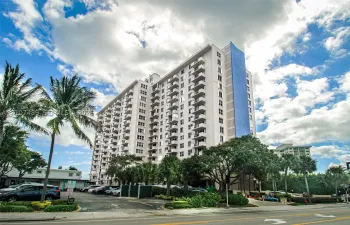 High-rise exterior featuring multi-level private balconies, white structural facade, and accent blue vertical panelling