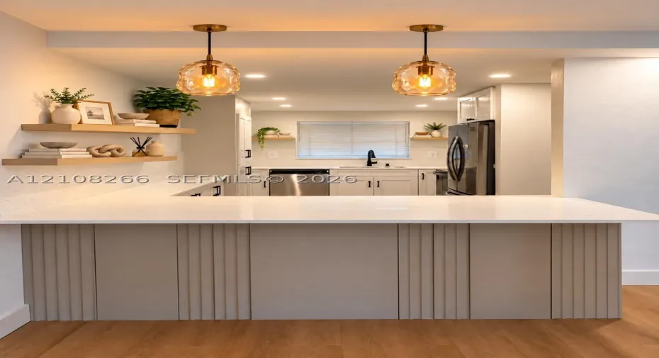 Kitchen featuring a quartz countertop peninsula with vertical slat paneling, dual glass pendant lights, light wood floating shelves, and recessed ceiling lighting