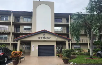 Multi-story building exterior featuring a tiled gable roof, private balconies with metal railings, and a central architectural tower element