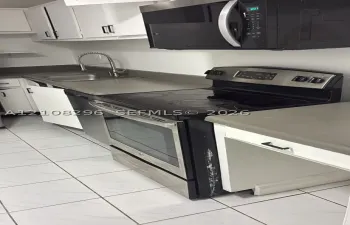 Kitchen featuring white cabinetry, stainless steel microwave, black electric range with stainless steel trim, solid-surface countertops, and tiled flooring