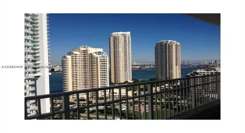 Private balcony featuring a metal railing with panoramic water and high-rise skyline scenery
