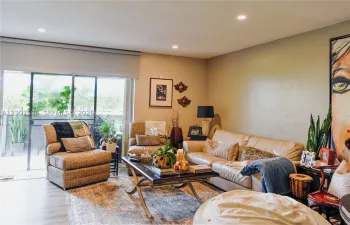Neutral wall finishes, recessed lighting, and large sliding glass door with a retractable roller shade, featuring wood-finish flooring