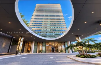 High-rise exterior featuring a circular porte-cochère, recessed lighting, glass-paneled balconies, floor-to-ceiling glass entrance, and a paved motor court