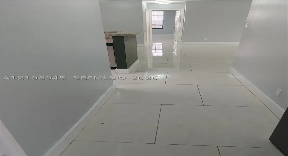 Large-format polished tile flooring featuring a neutral finish and a peninsula with a stone-composite countertop