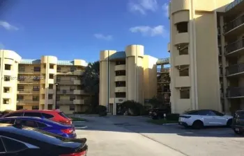 Multi-story building exterior featuring curved architectural towers, metal roofing elements, and private balconies with railings