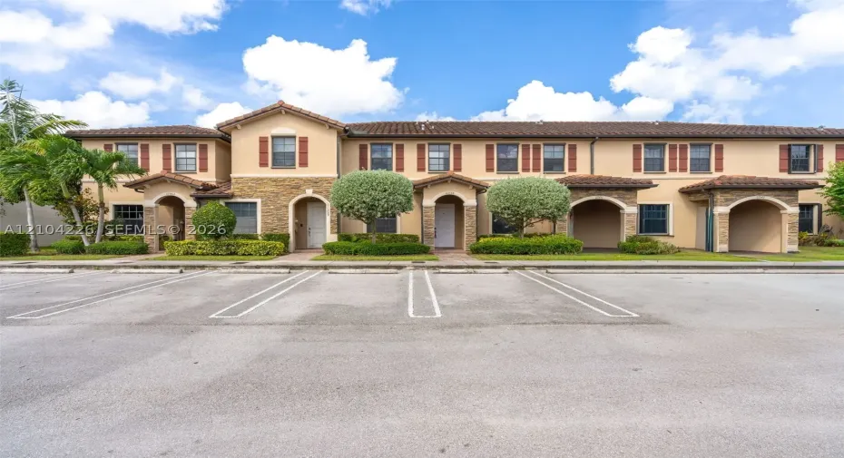 Stucco exterior featuring stone veneer accents, arched entryways, tile roof, and shuttered windows