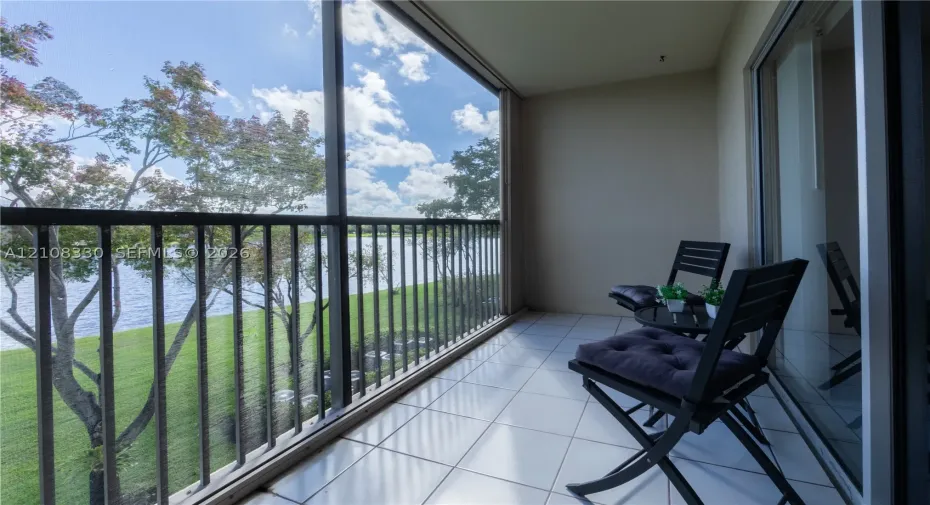 Screened-in balcony featuring tile flooring, metal railings, and direct water frontage