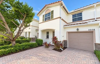 Stucco exterior featuring decorative stone veneer accents, arched entryway, paved driveway, and tile roofline