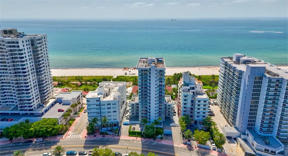 Aerial perspective featuring high-rise coastal architecture with balconies and direct proximity to the sandy shoreline and oceanfront