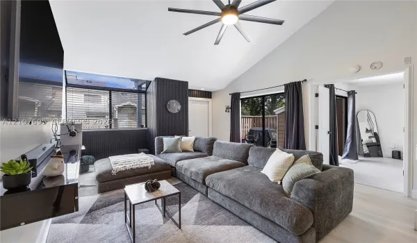 Vaulted ceiling featuring a central multi-blade ceiling fan