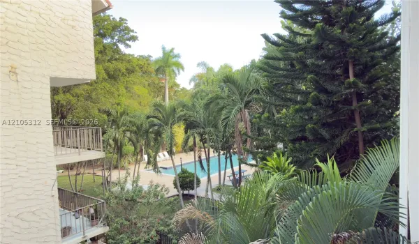 Outdoor space featuring an in-ground swimming pool, multi-level metal-railed balconies, and mature landscaping including palm and evergreen trees