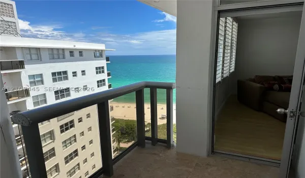 Covered balcony featuring stone flooring and a railing with glass panels, showcasing ocean and coastline scenery
