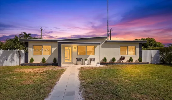 Single-story exterior featuring a low-slope roof, stucco siding, geometric glass-panel front door, and a concrete walkway