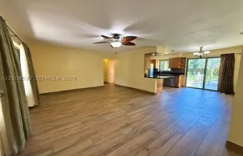 Open-concept interior featuring wood-finish tile flooring, a palm-leaf style ceiling fan, dark cabinetry, and sliding glass doors