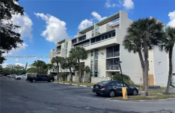 Multi-story residential building exterior featuring concrete facade, screened balconies, and decorative lattice screening