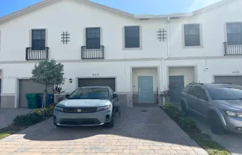 Stucco exterior featuring multi-level iron Juliette balconies, paved driveway, integrated garage, and decorative iron wall accents
