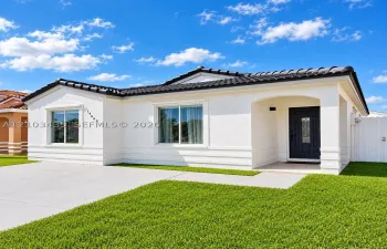Stucco exterior featuring horizontal banding, a dark-toned tile roof, dual-pane windows, a recessed entry with a paneled front door, and a concrete driveway