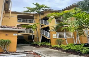 Stucco exterior featuring multi-level arched balconies, white railings, tile roofing, and mature palm landscaping